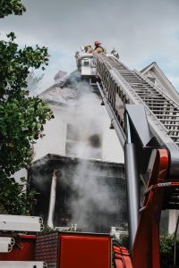 a house fire being put out by firefighters on a ladder